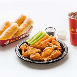 a plate of wings, carrots, celery sticks, and a drink