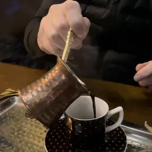 a person pouring a cup of coffee