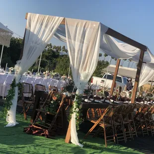 draped cabanas with farm tables and bamboo chairs
