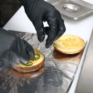 a person putting toppings on a sandwich