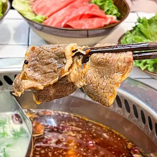 chopsticks holding a piece of meat