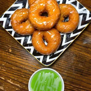 a plate of glazed donuts and a cup of green tea