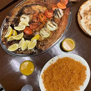 a whole fish on a platter with vegetables and rice