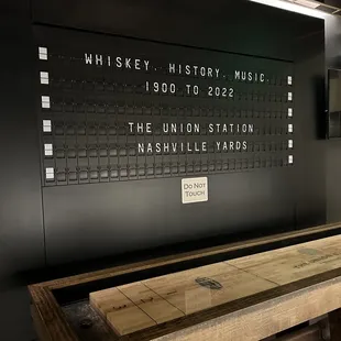 a wooden bench in front of a wall with a sign that reads whiskey history, music, and the union station nashville yards