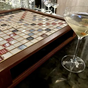 a glass of wine next to a scrabble board