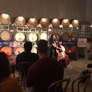 a woman playing a guitar in a wine cellar