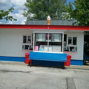 a blue and red bench in front of an ice cream shop