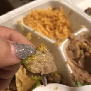 a hand holding a spoon full of food