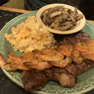 My husband's special of the New York strip and shrimp with their seasoning on top and sides of hash brown casserole and mushrooms.