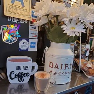 a cup of coffee and a vase of daisies