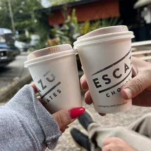 two people holding coffee cups