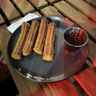 a plate of churros on a wooden table