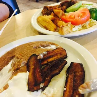 Plantains, crema, beans on the front plate. Fried yucca on the back plate with chicharon.