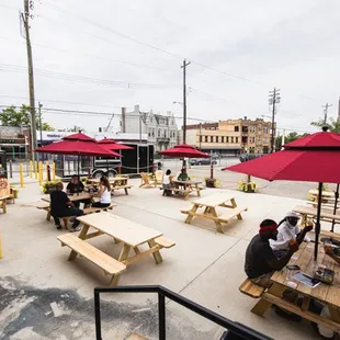 several people sitting at picnic tables under umbrellas