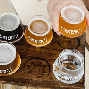 a flight of beers on a wooden tray