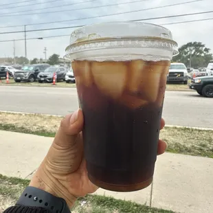 a hand holding a cup of iced coffee