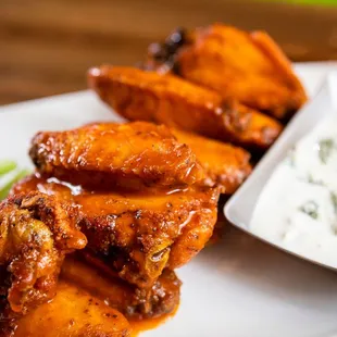 a plate of chicken wings, celery and dip