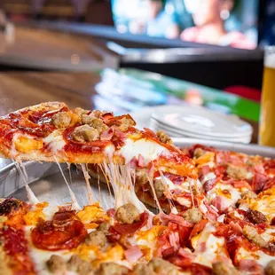 a person taking a slice of pizza