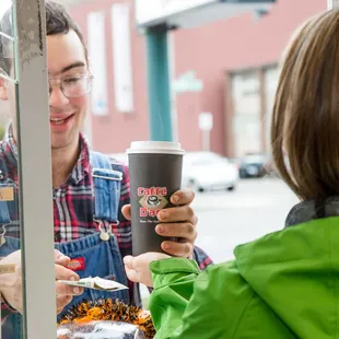 a man handing a cup of coffee to a woman