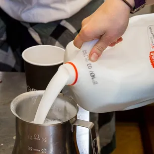 a person pouring milk into a pot