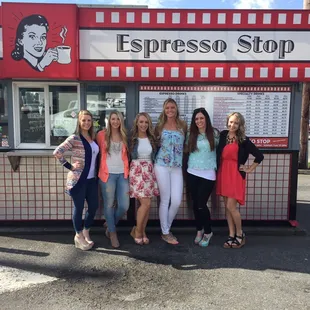 a group of women standing in front of a coffee shop