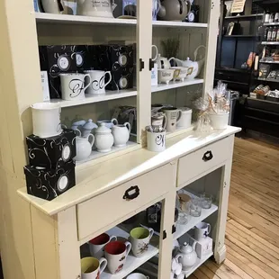 a white china cabinet with cups and saucers