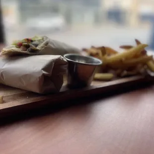 a burrito and french fries on a cutting board