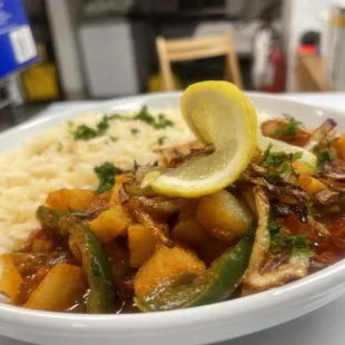 a bowl of food with rice and a lemon slice