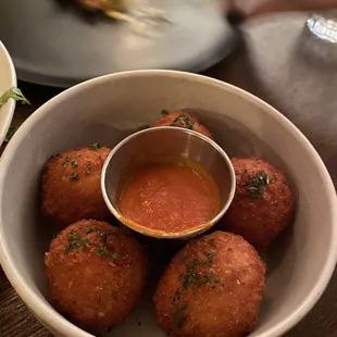 a bowl of deep fried meatballs and a bowl of sauce