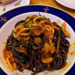 Squid ink pasta with spicy red sauce, calamari, and pork belly