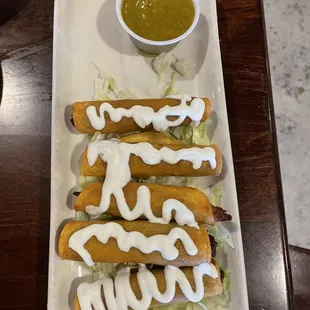 a plate of hot dogs and a bowl of sauce