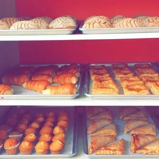 Traditional vanilla conchas, sweet bavarian cream cones, pineapple puff pastry, bavarian filled churros, muffins, and cream cheese turnovers