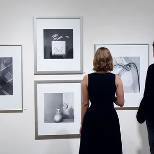 Two gallery patrons look at the gelatin silver prints of photographer, Frances Murray.