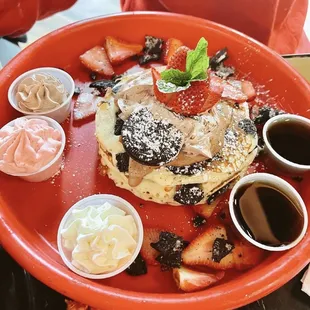 a plate of pancakes with strawberries and syrup