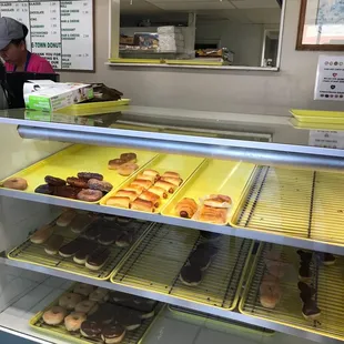 a woman behind the counter of a donut shop