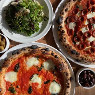 two pizzas and a salad on a table
