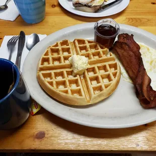 Belgian waffles, eggs, bacon, cup of black tea