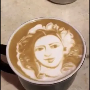 a cup of coffee with a drawing on it