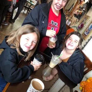 three girls sitting at a table with drinks