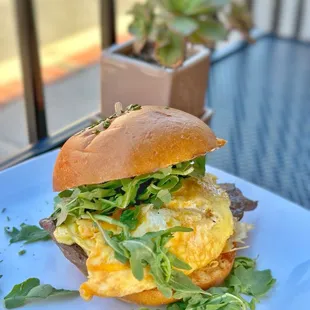 Steak and Eggs Sandwich - Skirt steak, chimichurri, arugula, Cheddar, soft scrambled eggs. Served on a brioche bun.