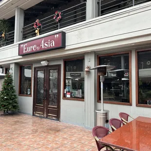 the outside of a restaurant with tables and umbrellas