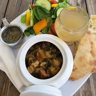 a bowl of soup, bread, and vegetables