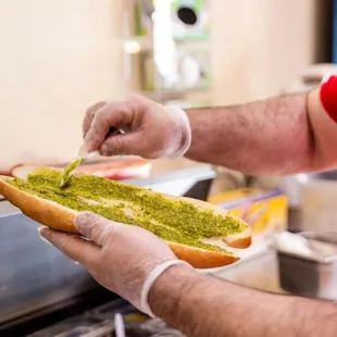 a man putting pesto on a hot dog