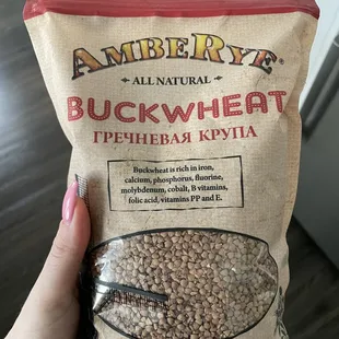 a hand holding a bag of buckwheat