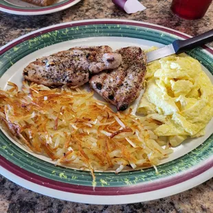 Pork chop with scrambled eggs and hash browns.