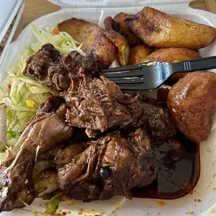 Brown stew chicken with sides of cabbage and plantain.