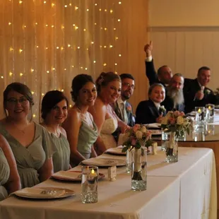 Head table in front of burlap wall with twinkle lights