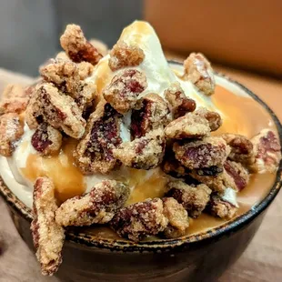 a bowl of ice cream with nuts and caramel