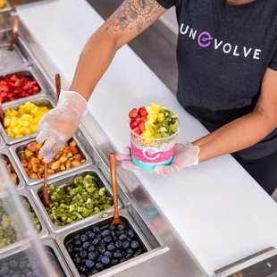 a woman preparing a bowl of fruit