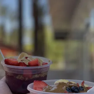 a hand holding a plastic cup of fruit and yogurt